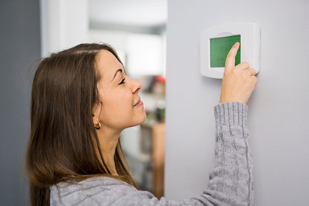 Woman set the thermostat at house.