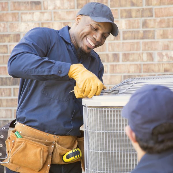 African American HVAC tech professional from Total Comfort happily repairing AC outdoor unit