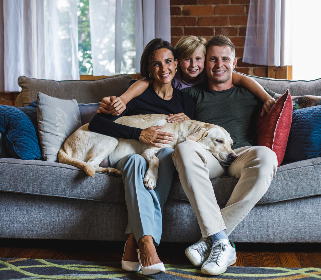 Mother, Father and kid with yellow lab sitting on gray couch