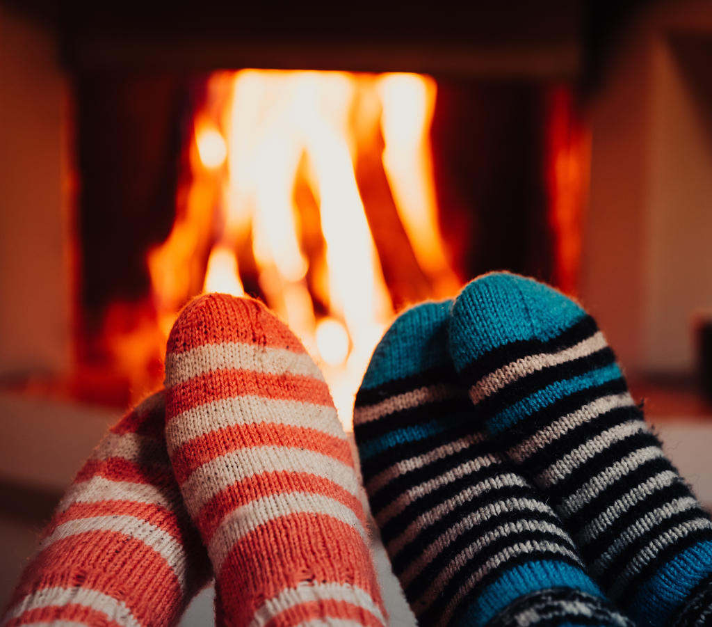 Two pairs of feet in striped socks warming in front of a fire place