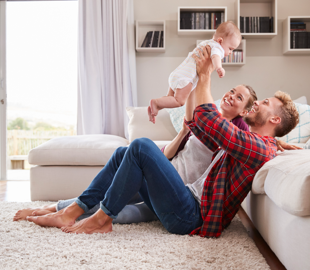 Young couple play with their toddler in sitting room
