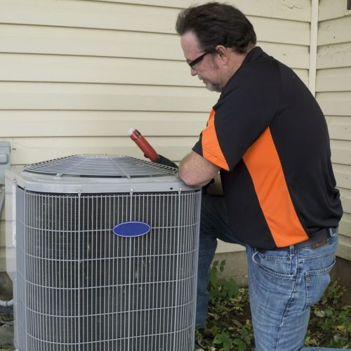 Repairman checking outside air conditioning unit for voltage